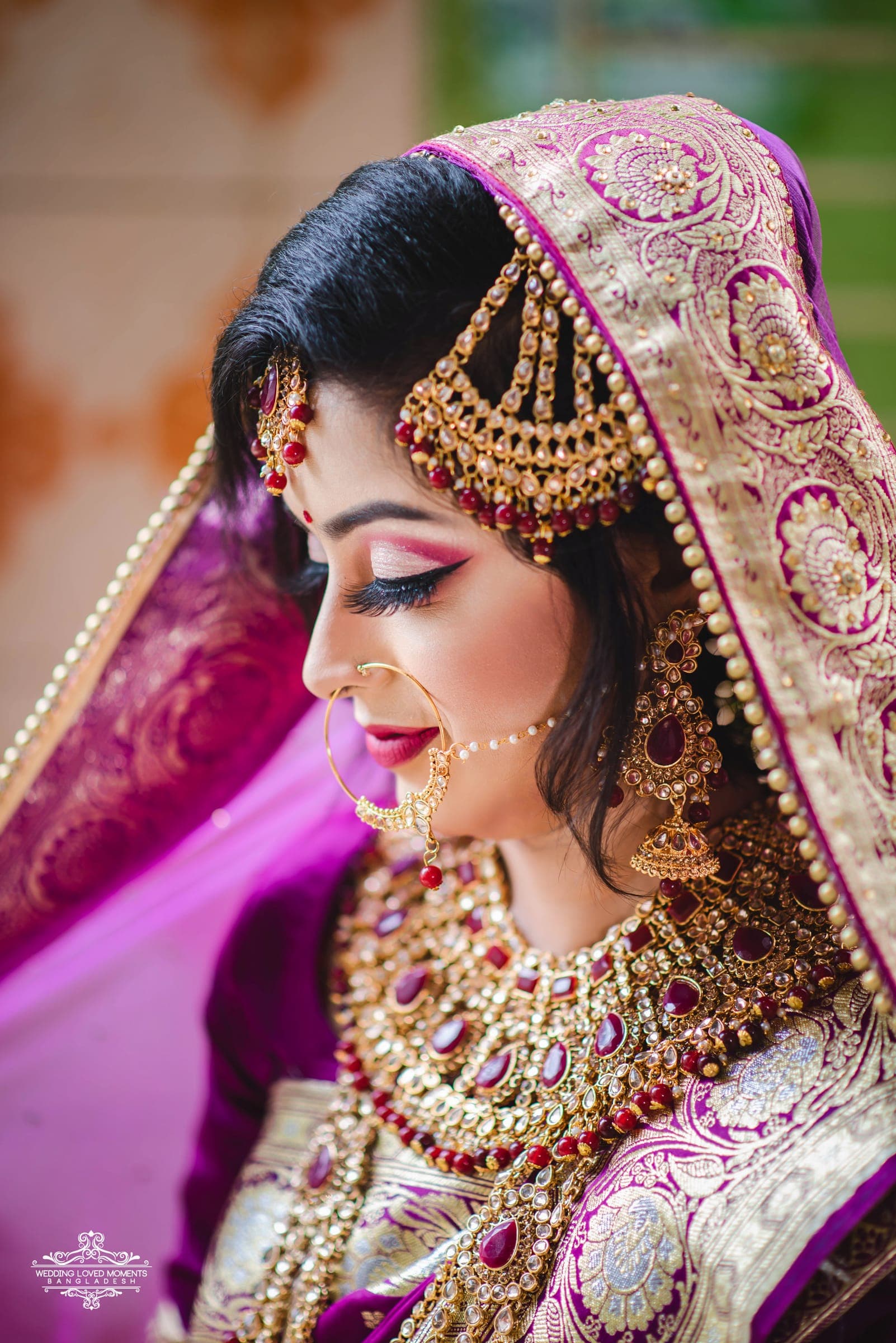 Profile of a bride in a purple and gold dupatta wearing a traditional nose ring and jewellery