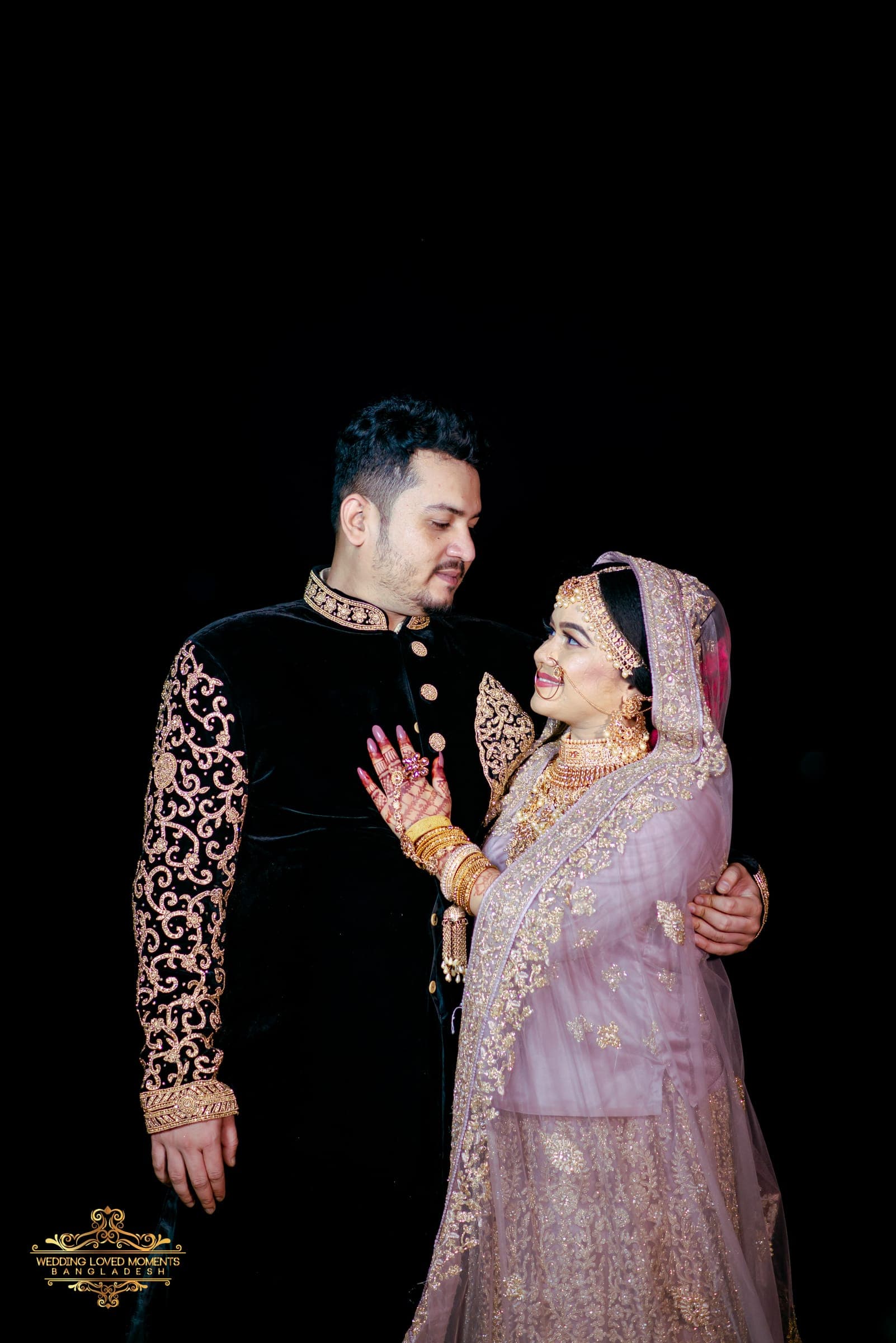 Groom embracing the bride from the side, both in embroidered evening attire