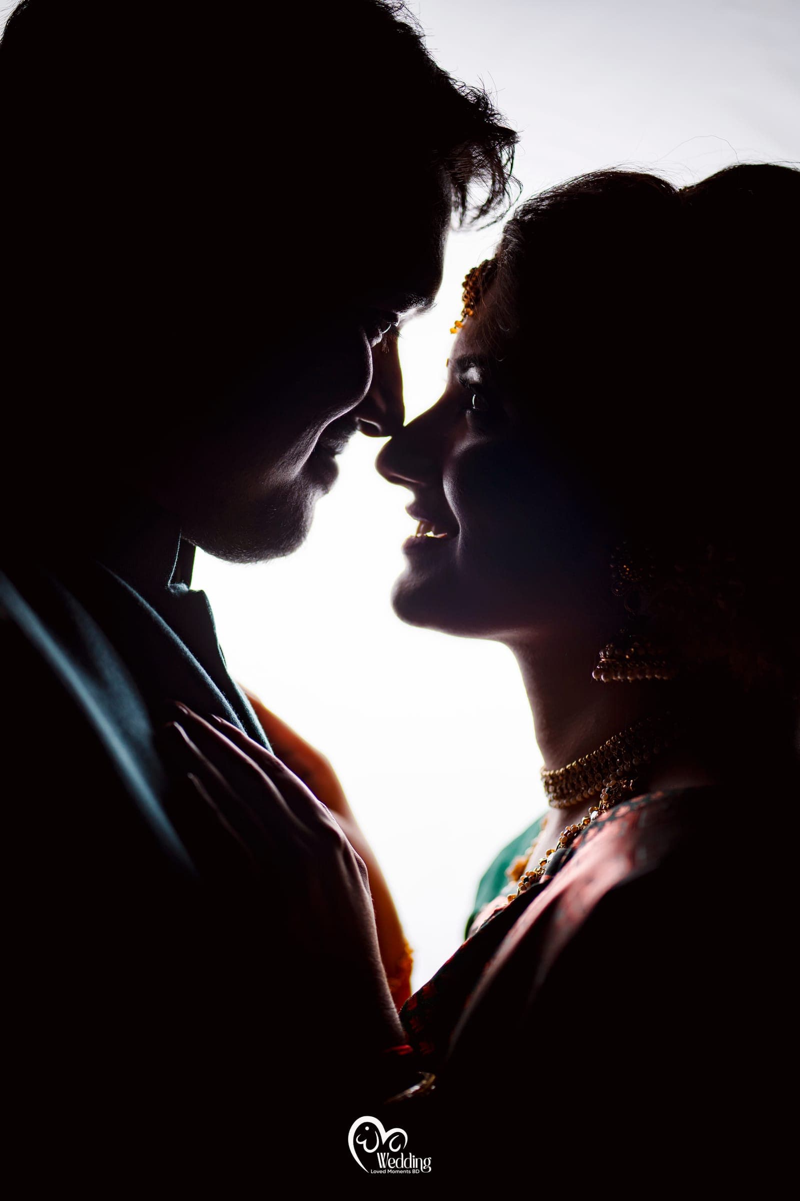 Silhouette of a couple about to touch foreheads against a bright window